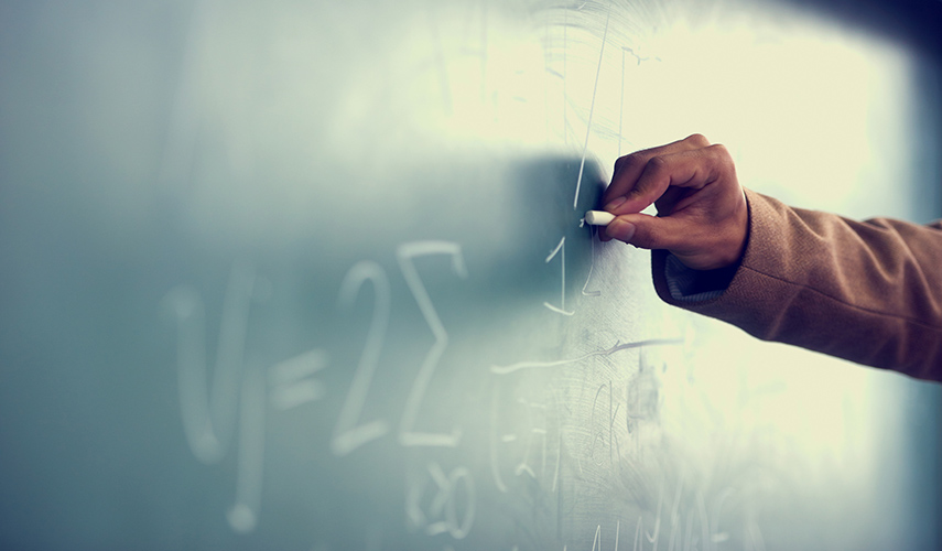 A hand writing a math problem on a chalkboard