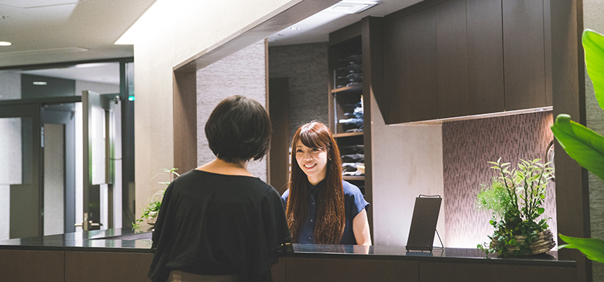 A receptionist speaks to a guest in a hotel lobby