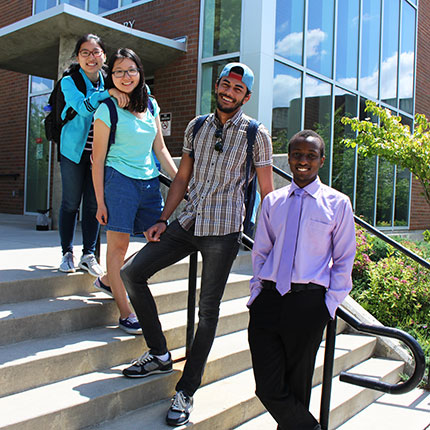 Group of students standing on outdoor stairs leaning against the railing
