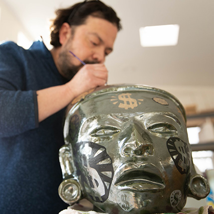 Artist Horacio Rodriquez working on a sculpture of a face