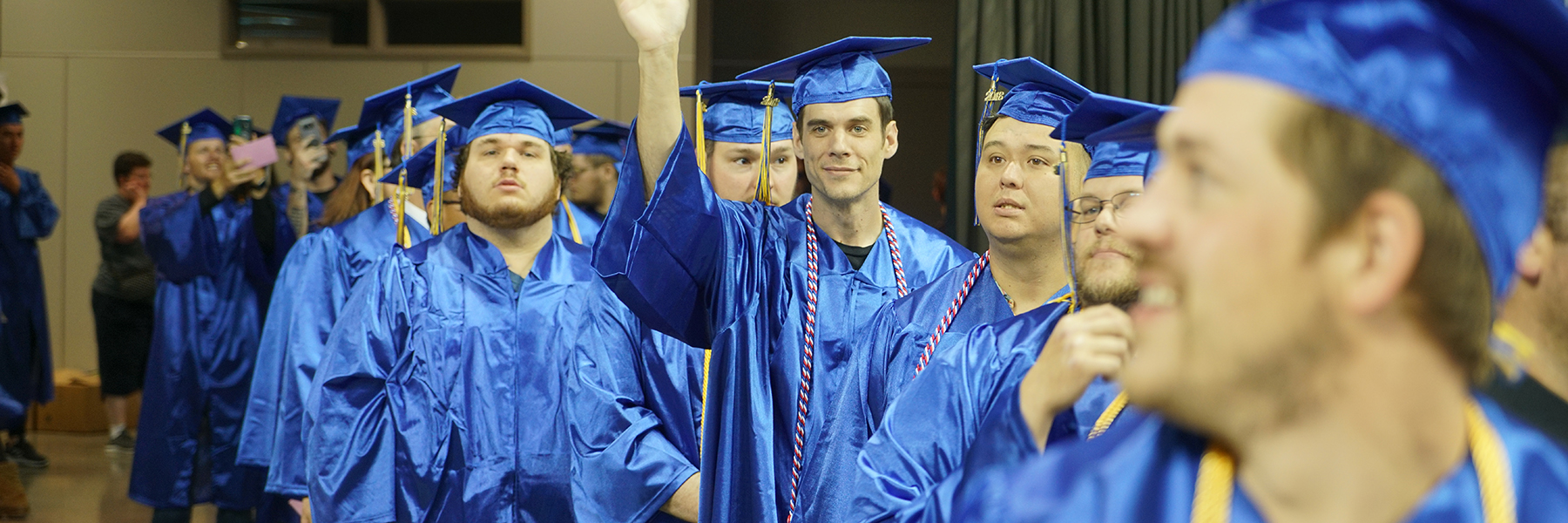 Students at Spokane Community College's 2018 graduation waving as they walk in to be seated
