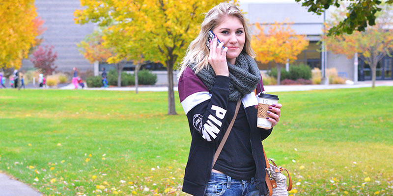 Girl walking with coffee in hand talking on her cell phone