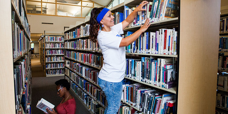 Picking a book out of a library shelf.