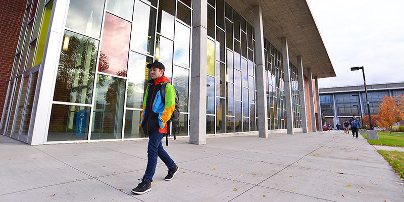 Student walking in front of the music building on the SFCC campus.