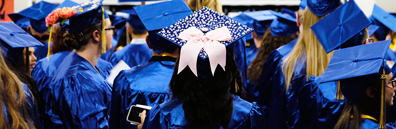 A decorated graduation cap amongs many other caps