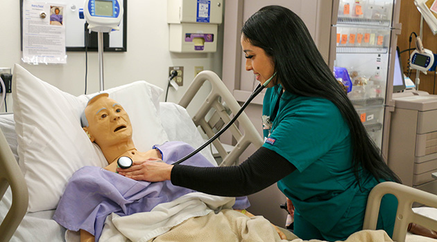 SCC Practical Nursing Student taking mannequin’s pulse with stethoscope.