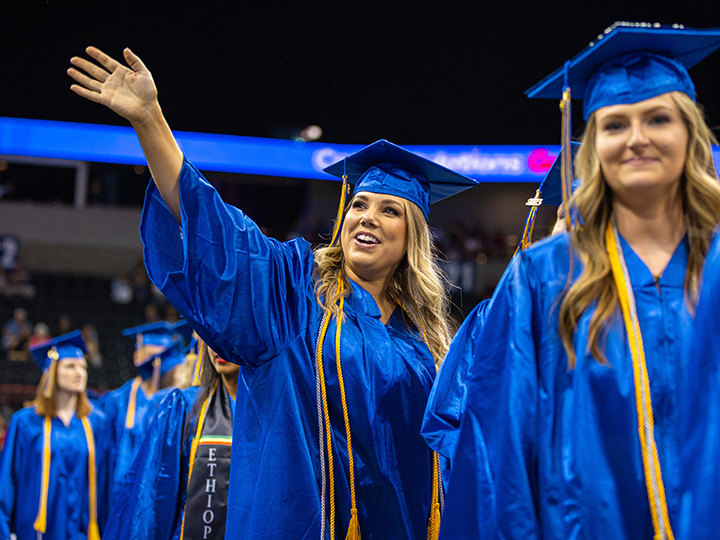 student waving during graduation.