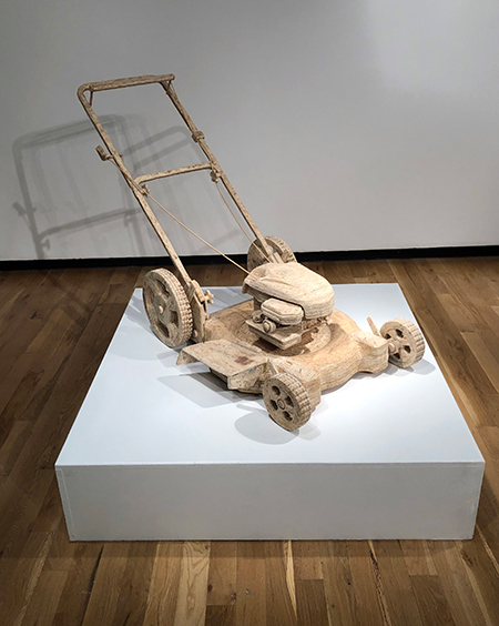 A wooden lawnmower on a white box by Artist Jim Zimpel