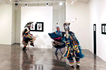 Three Native American performers, inside SFCC’s Fine Art Gallery, performing the Grass Dance to honor Indigenous People’s Day. This was part of the Masked Preservation exhibition by artist Chad “Little Coyote” Yellowjohn.