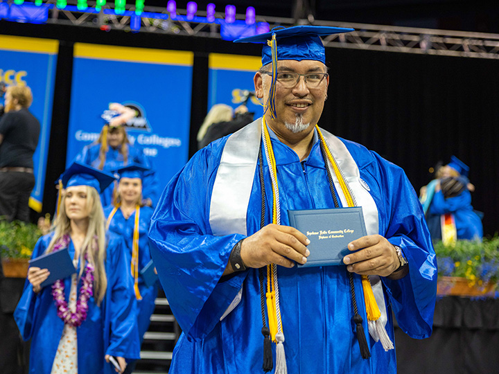student walking after receiving diploma during graduation.