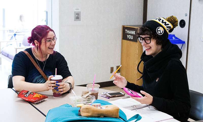 Two students laughing in the Falls Cafe dining area.