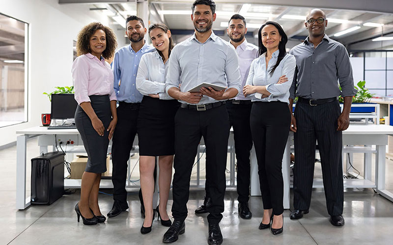 Successful Latin American business team working at the office while looking at the camera smiling.