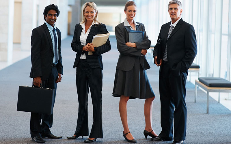 Happy team of business associates standing together at a hallway.