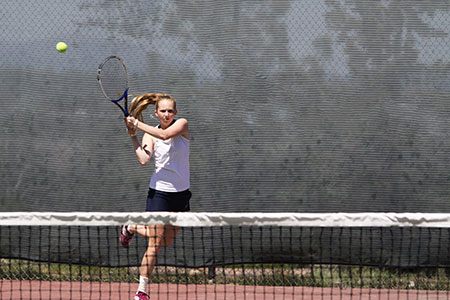 A female player swings her racket to hit a tennis ball