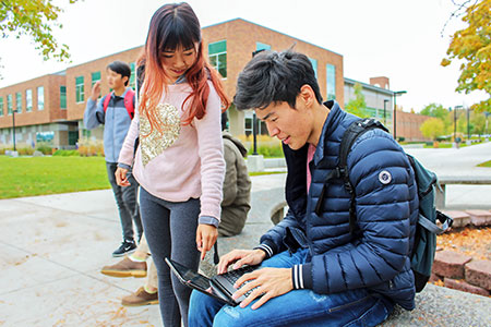 An international student pointing to a laptop.