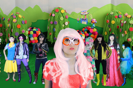 Artist JooYoung standing in a forest of her artwork among 6 version of herself wearing different costumes