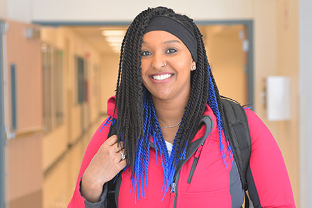 Female student smiling in the hallway.