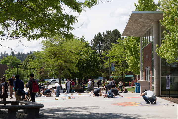Students creating chalk drawings on sidewalk outside of the Library