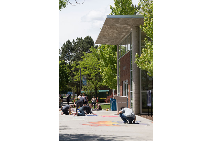 Students creating chalk drawings on sidewalk outside of the Library