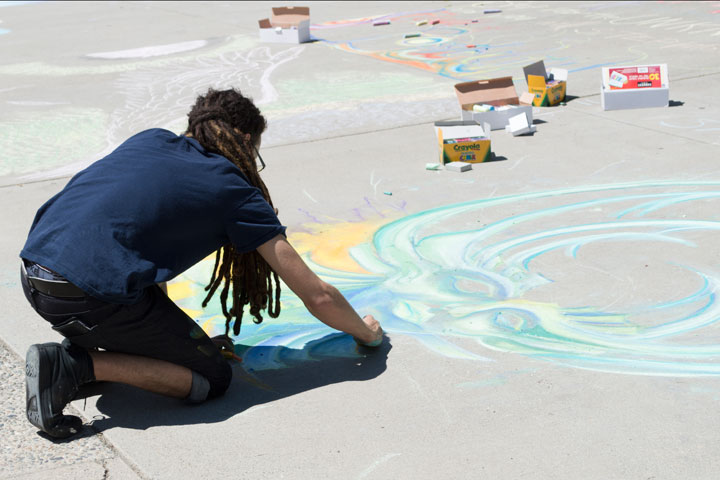 Student creating chalk art in fron of the library
