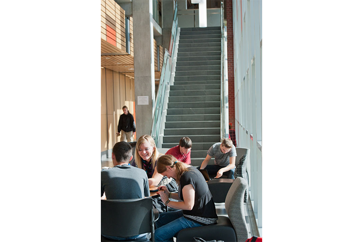 Five students seated together inside Music Building lobby