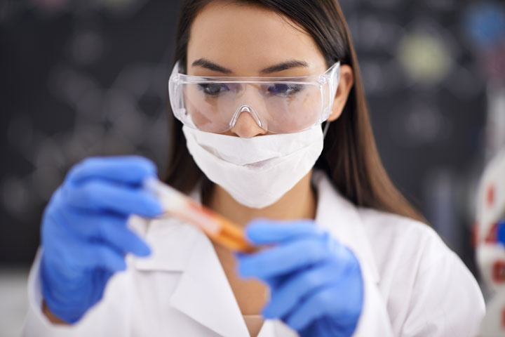 Chemical engineer with mask and, gloves holding vial