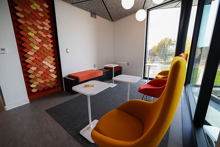A study area with colorful chairs, tables, and artwork on wall.